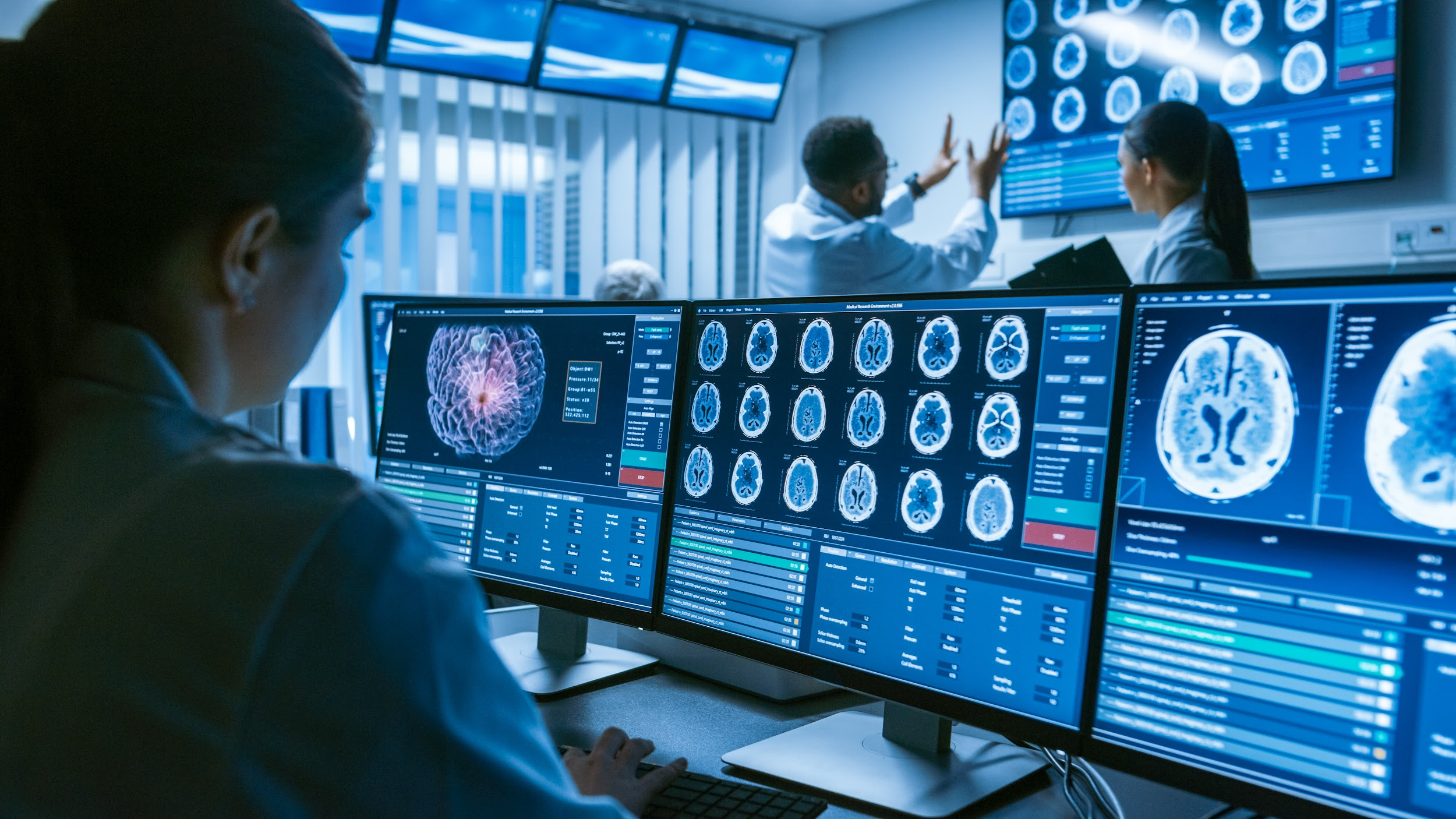 Scientists in a control room analyze brain scans on multiple monitors. The room's high-tech atmosphere conveys focus and collaboration.