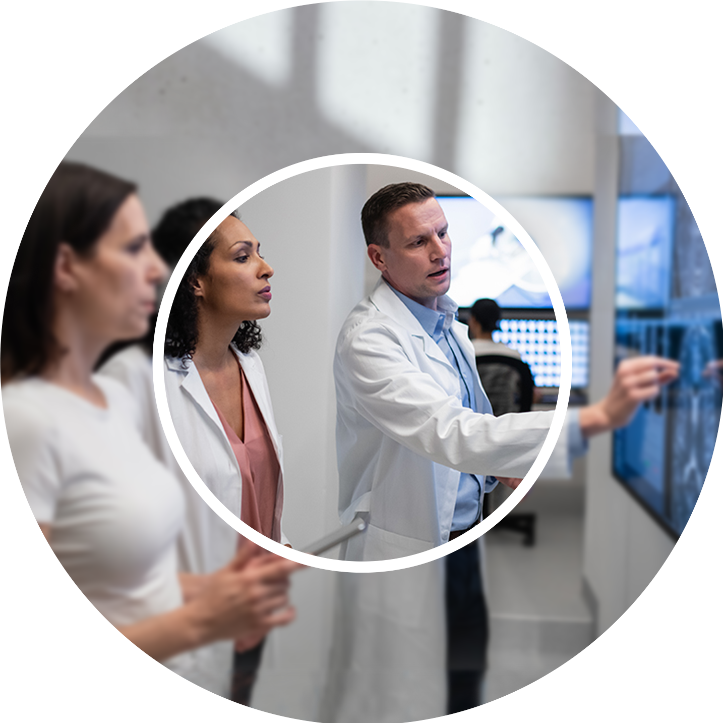 Group of three professionals in lab coats examining data on large screens, conveying focus and collaboration in a modern, high-tech setting.